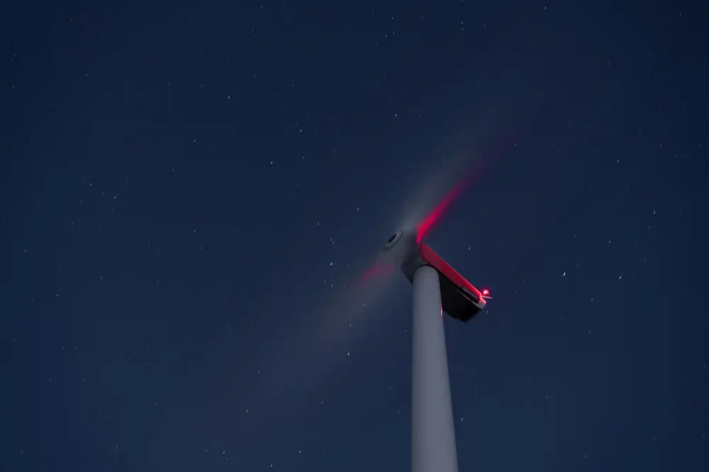 Wind turbine with a red warning light glowing on top of the nacelle