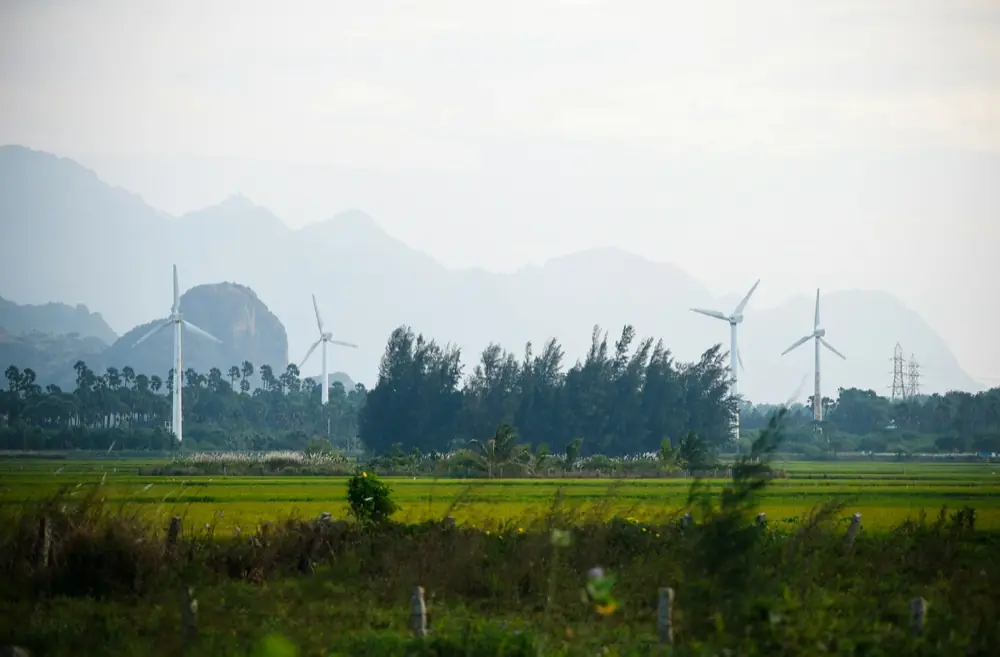 Wind turbines across a rural landscape with mountains behind