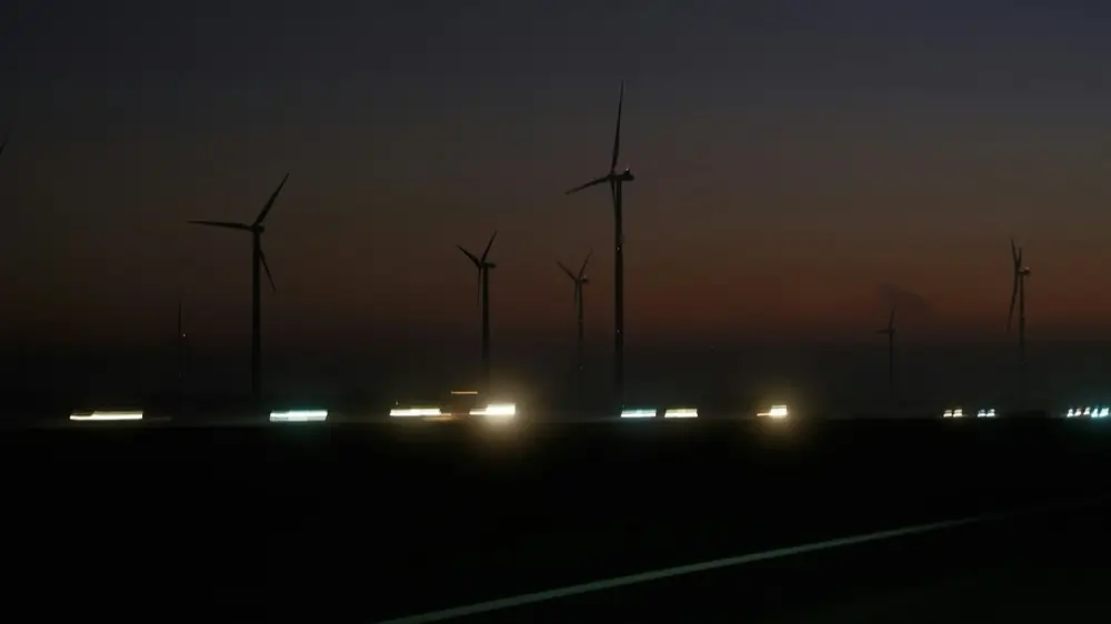 Wind farm at night with turbines lit against a dark sky